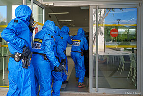 Cinq policiers armés portant une combinaison et un masque à gaz pénètrent dans un lycée